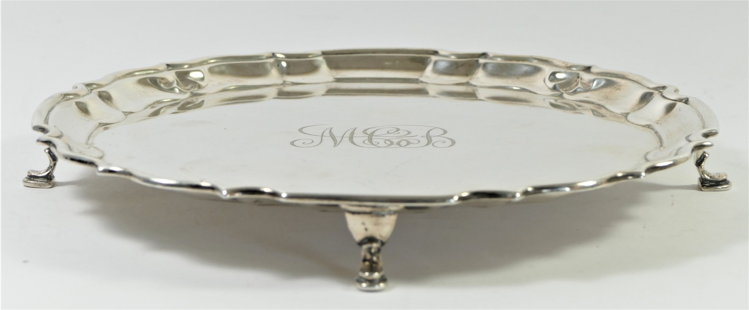 A silver waiter, by Barker Bros, Chester 1917, raised on four pad feet, monogrammed, 21cm, 358gm