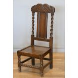 An 18th century and later oak hall chair, with carved S scroll top rail, panel back with turned