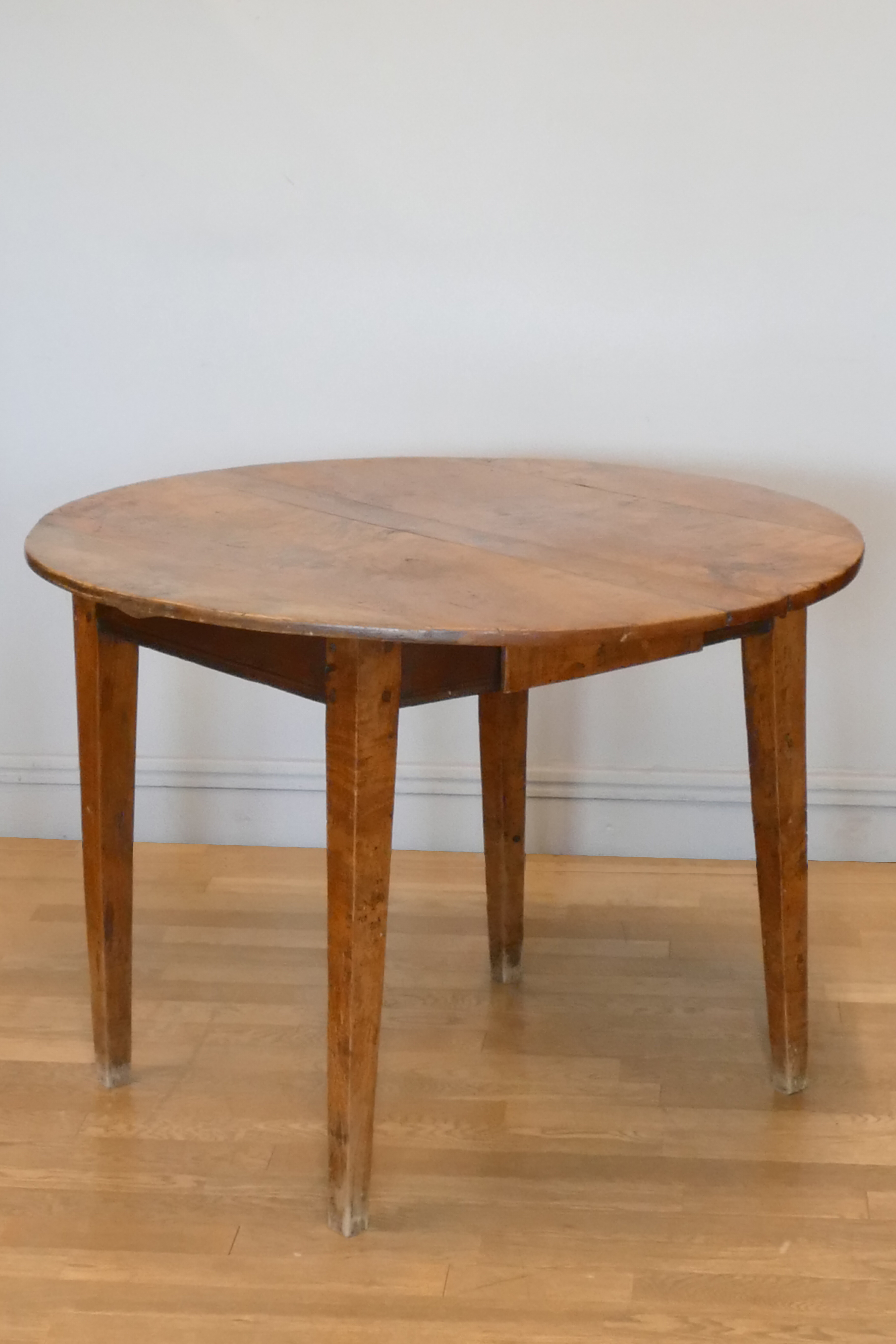 An 18th century country made circular elm table, five section top, frieze drawer, square tapering