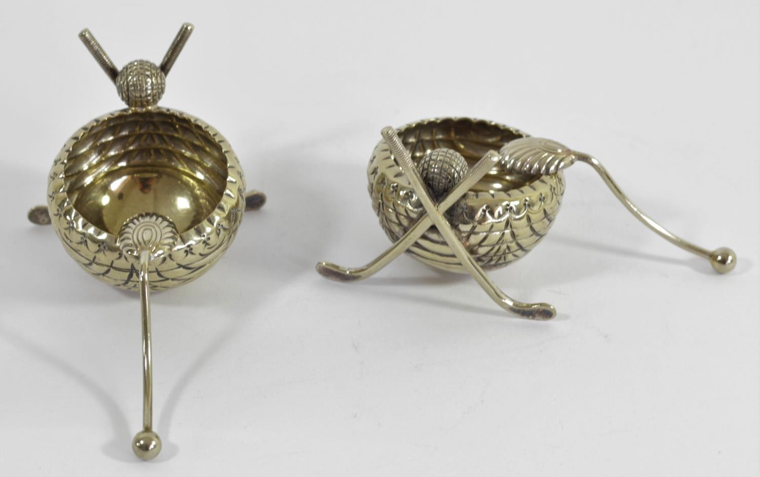 A Victorian pair of electroplated novelty salt pots, in the form of crossed hockey sticks with a