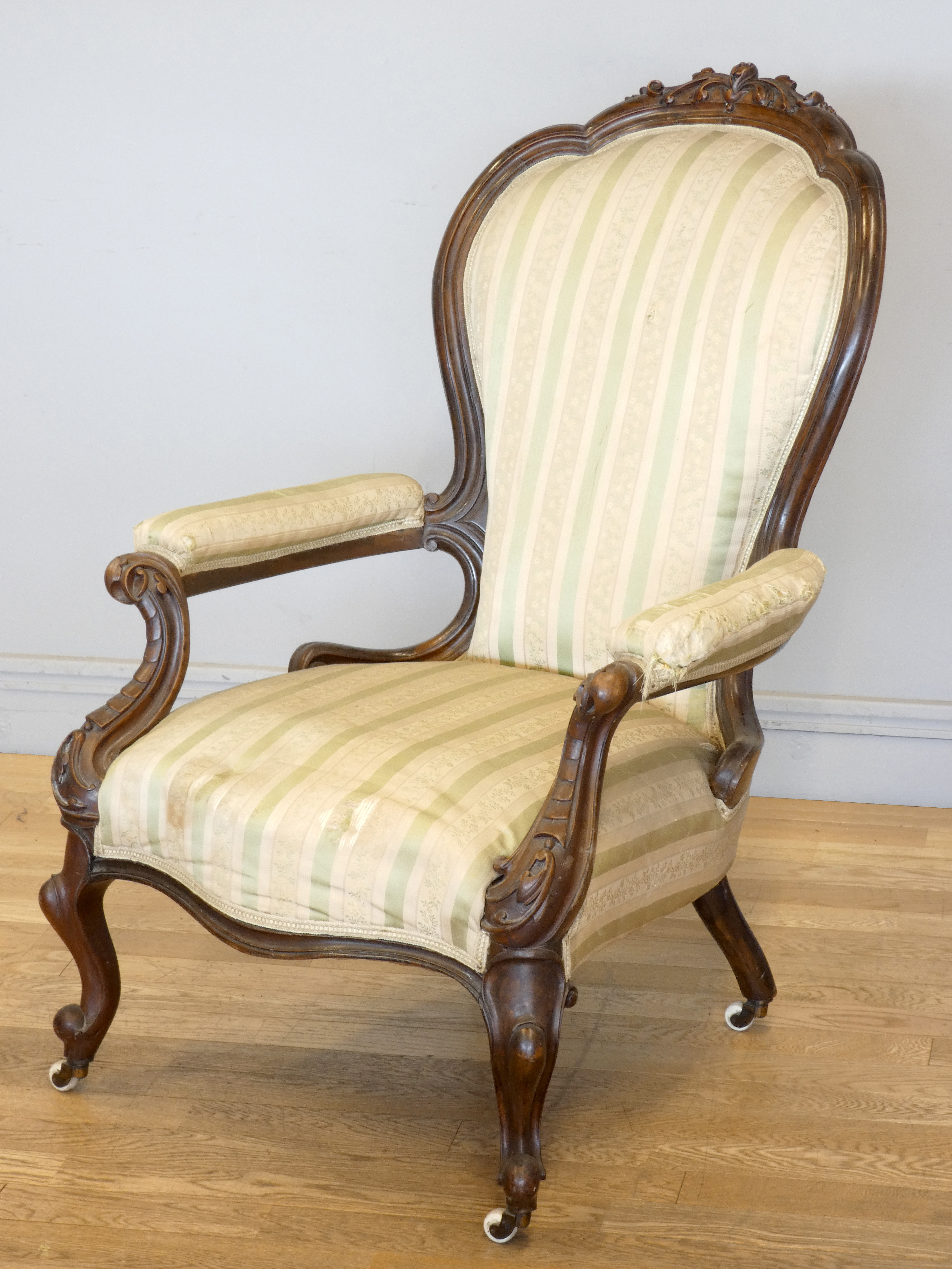 A Victorian carved mahogany button back parlour chair, padded arms, with carved cabriole front