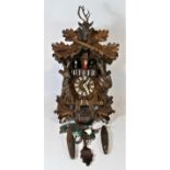 A Black Forest mechanical cuckoo clock, with central carved deer head & two rifles, made in Germany.