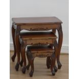 A nest of three hardwood tables of Eastern origin, having carved decoration to the edges standing on