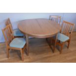 A Nathan round teak dining table & four chairs, incorporating an integral leaf, raised on tapered