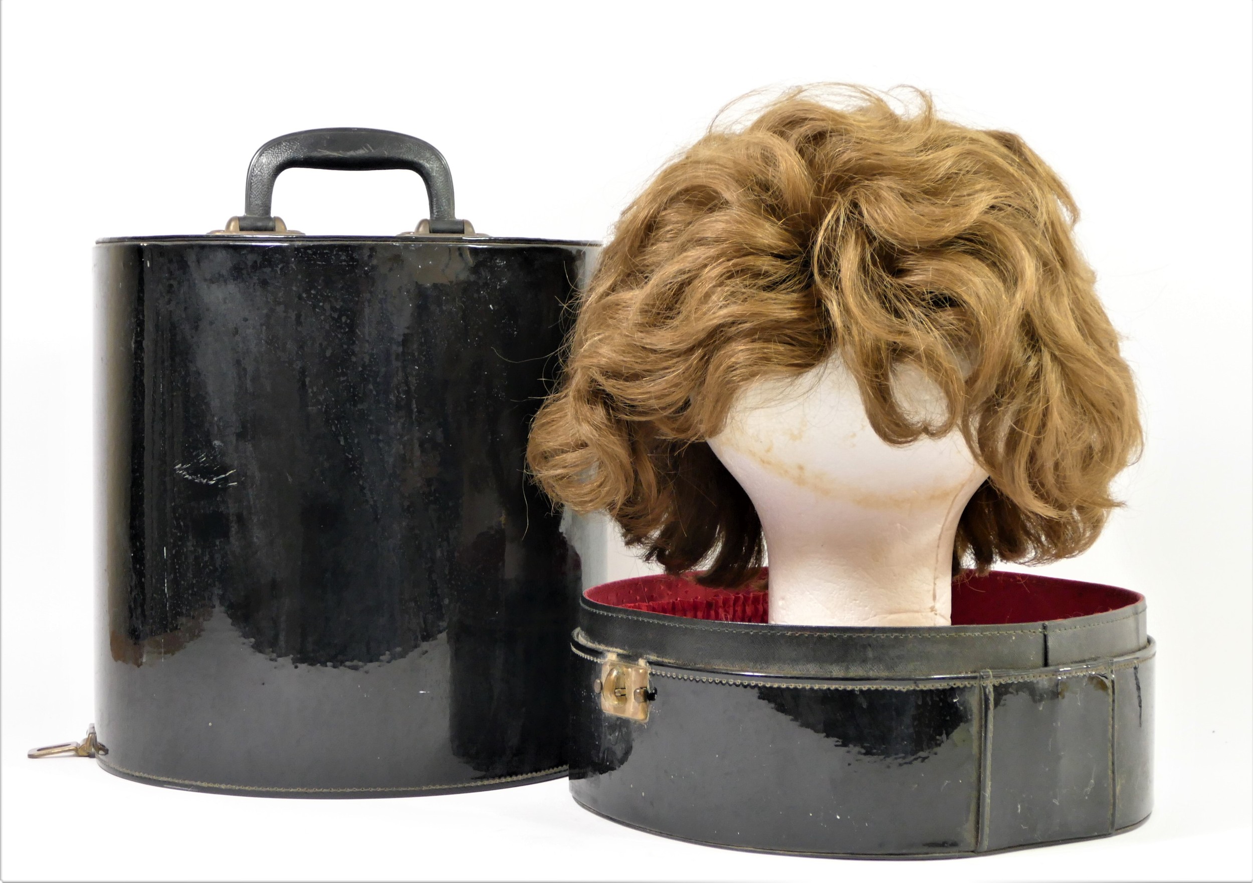 Short, mid brown 1960's style wig in a black patent travel case , 35 x 27cm.