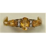 A 9ct gold citrine three stone ring with diamond points between, S, 2.3gm