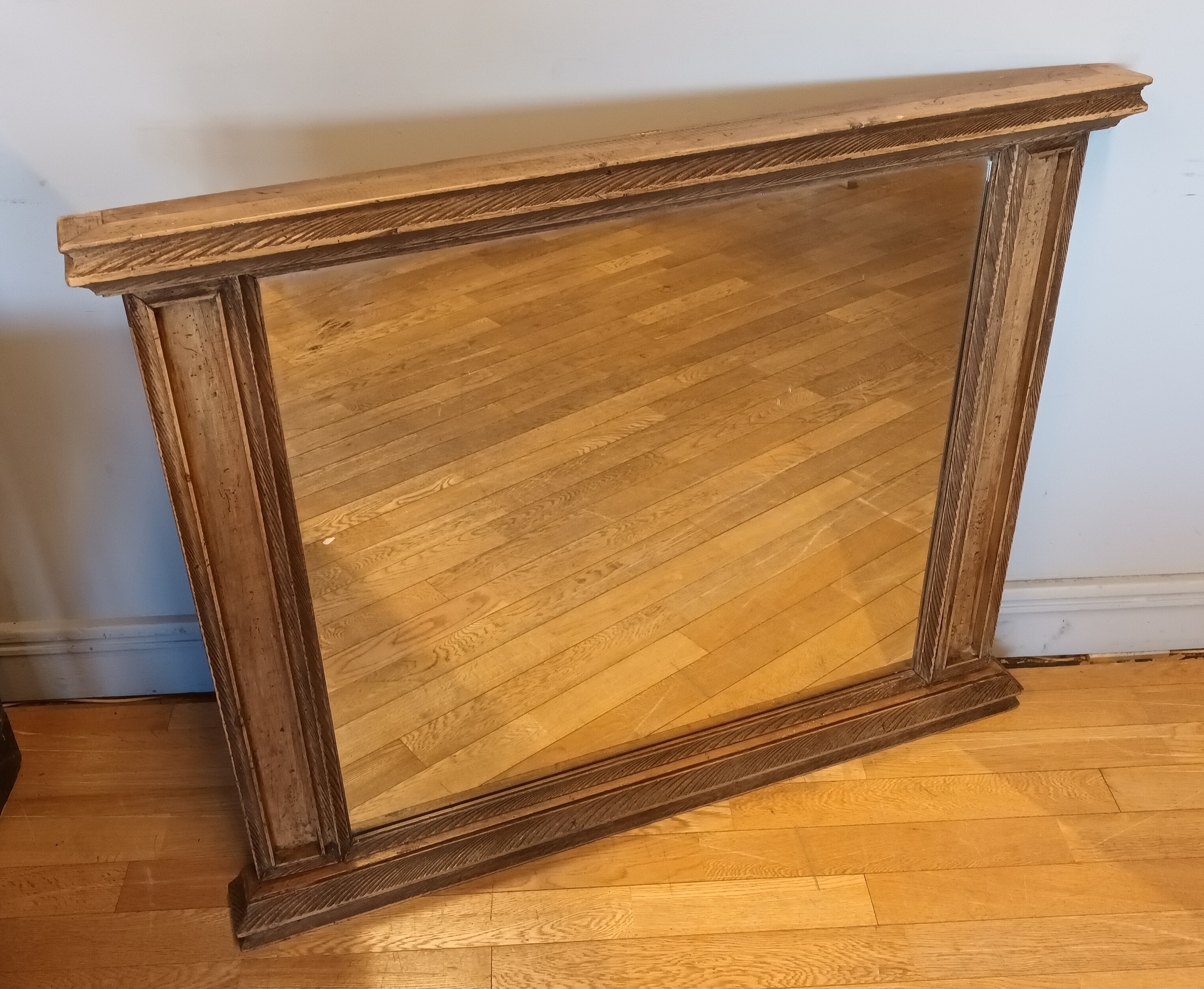 A large modern stained pine overmantle mirror, carved decoration with recessed columns to each side.