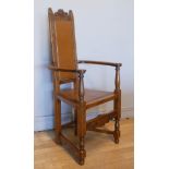 An Arts & Crafts style oak Shakespeare chair, high-backed bow-armed with triangular seat and