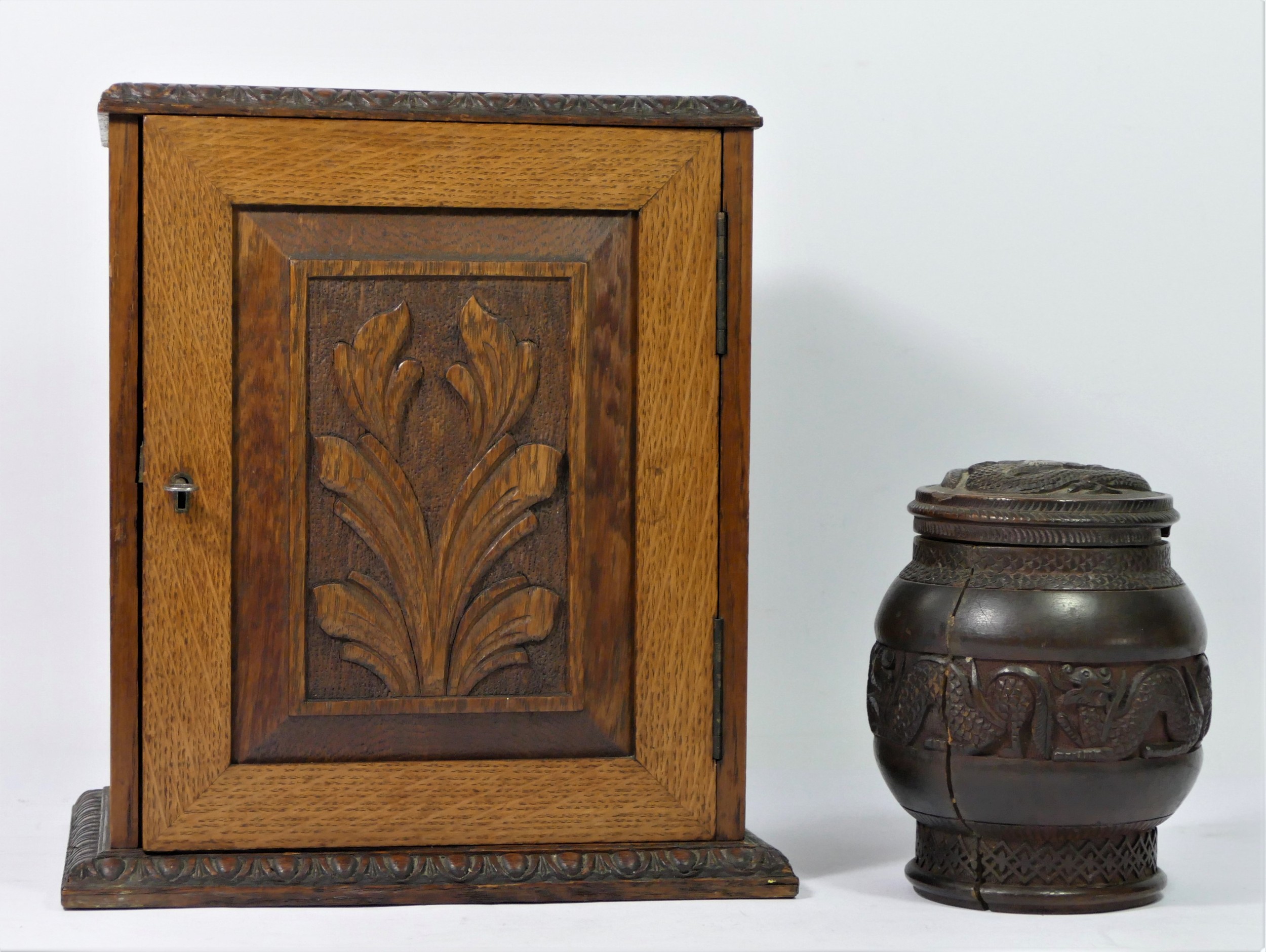 A late Victorian smokers cabinet, having carved panel door enclosing a fitted interior,