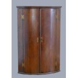 A George III oak corner cupboard, the plain doors opening to reveal three shelves.