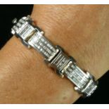 A white gold and diamond set panel link bracelet, channel set with tapering baguette stones,