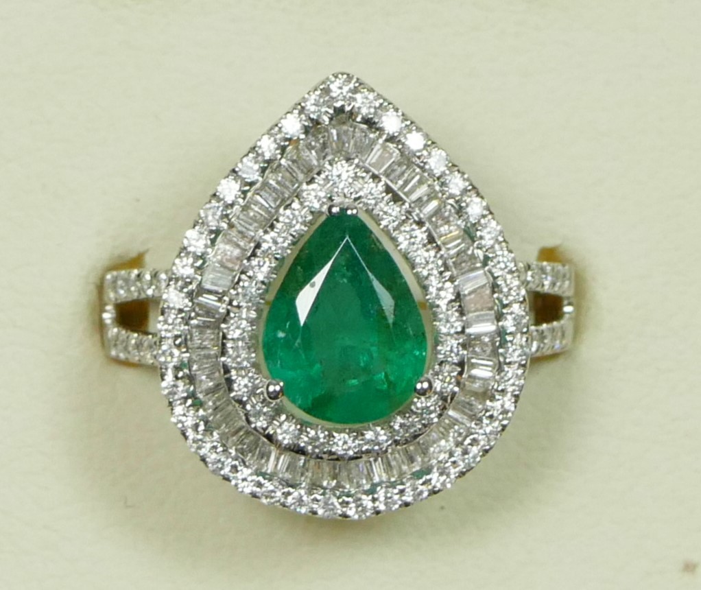An 18ct white gold emerald and diamond cluster ring, claw set with a pear cut stone, approximately