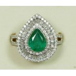 An 18ct white gold emerald and diamond cluster ring, claw set with a pear cut stone, approximately