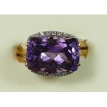 A 9K gold, amethyst and brilliant cut diamond dress ring, claw set with a mixed cut stone, flanked