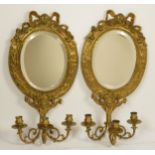A pair of cast brass Girondel wall mirrors, with ribbon and bow surmount, supporting three