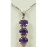 A 9ct gold amethyst three stone pendant, diamond points between, chain, 2.8gm