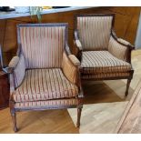 A pair of mahogany framed Regency style armchairs with carved top rail, raised on tapering legs,