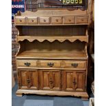 A kitchen dresser, two shelves, one of which contains two drawers, one drawer over three hinged