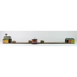 A tinplate toy, train track consisting of four trains on a wire travelling between two stations,