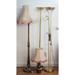 Three standard lamps to include two modern brass uplighters, a turned wood example and a table lamp.