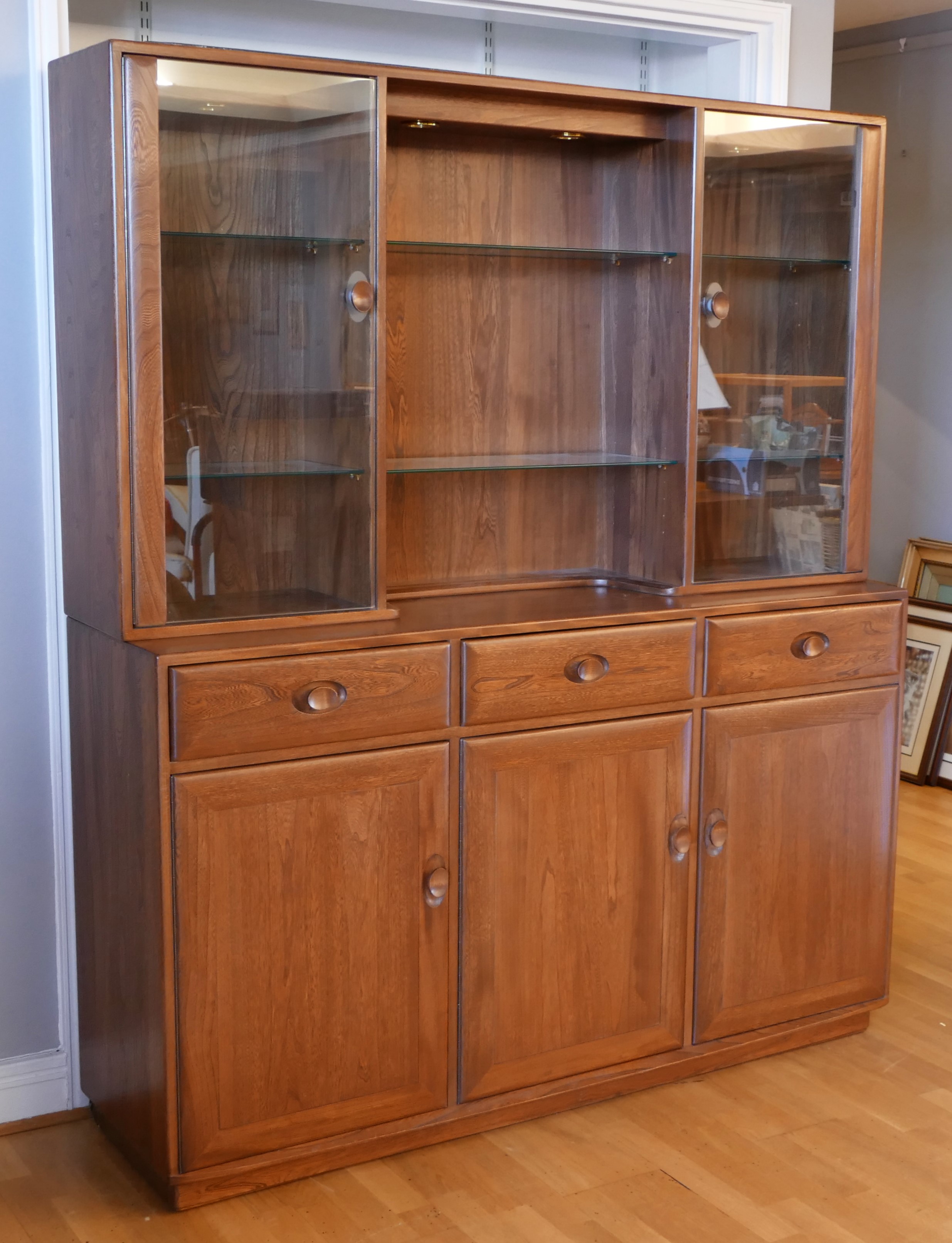 Ercol - elm display cabinet, two glazed doors flanking glass shelves with lighting above, the base