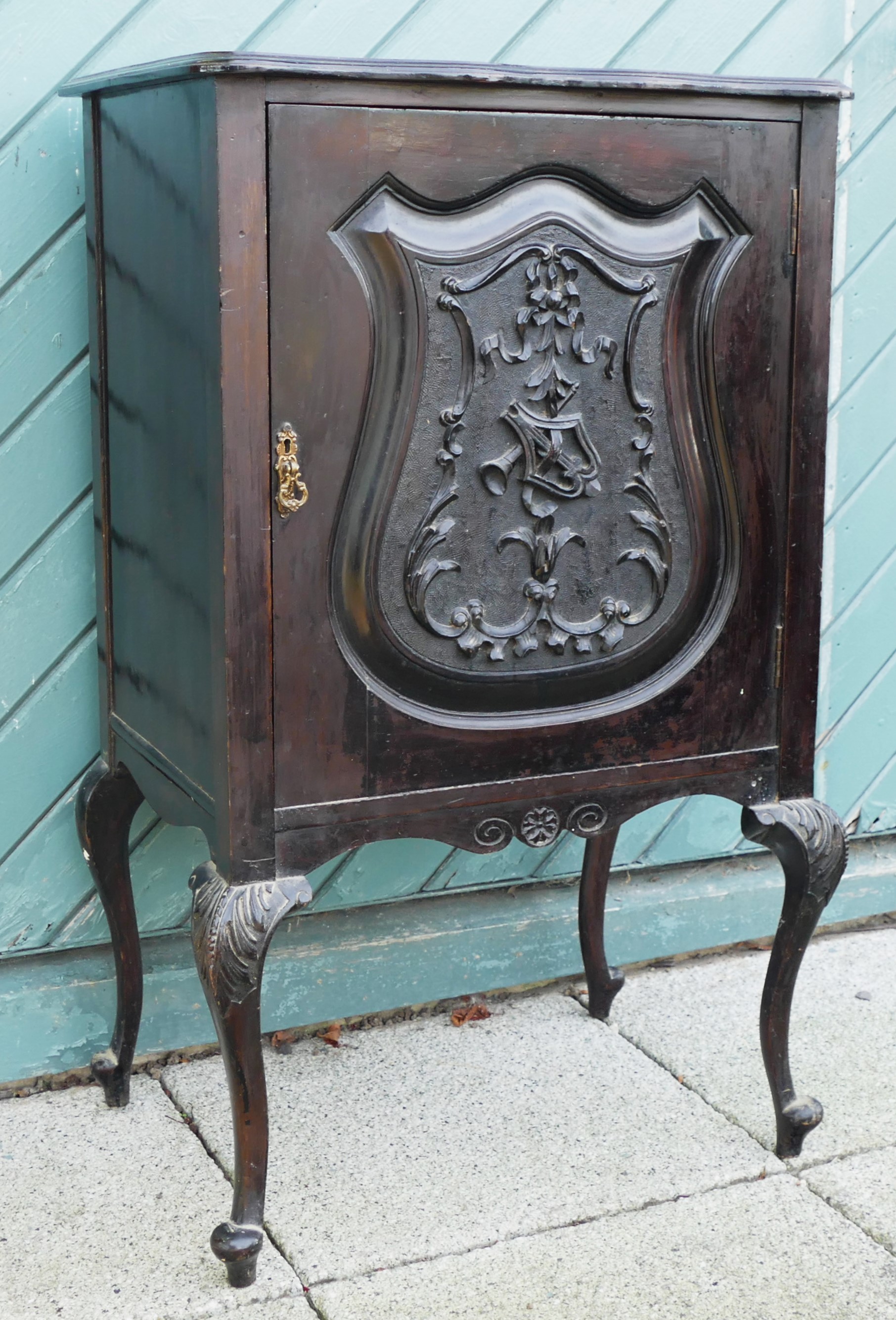 A French Louis XIV style ebonised music cabinet having scalloped edge top above a carved panel door,