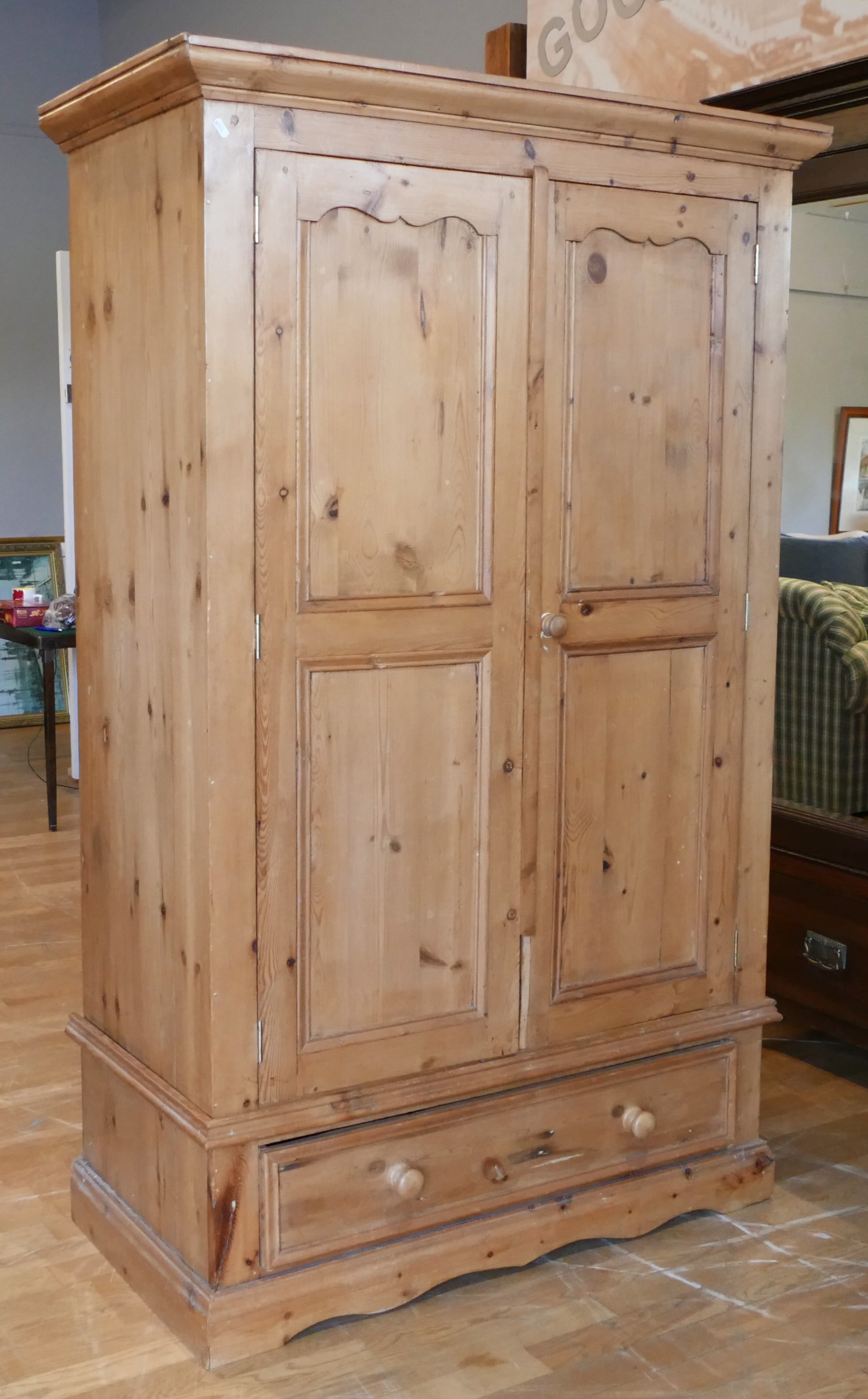 A modern rustic pine single wardrobe, twin doors with single long drawer below raised on a