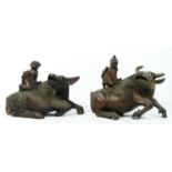 A Chinese pair of carved hardwood recumbent water buffalo with two riders, glass eyes, 22 x 18cm.