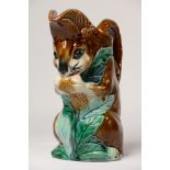 An early 20th century French Faience pitcher in the form of a squirrel eating a nut, 22cm tall,