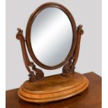 A Victorian mahogany dressing table mirror, the oval plate with foliate carved cresting, held in