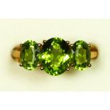 A 9ct gold and three stone peridot ring, the largest 10 x 8mm, U, 3.5gm