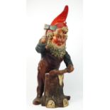 A late 19th/early 20th century pottery gnome figurine, chopping wood with an axe, 46cm