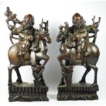 A Chinese pair of carved hardwood and silver wire inlaid Immortals riding stags, black glass eyes,