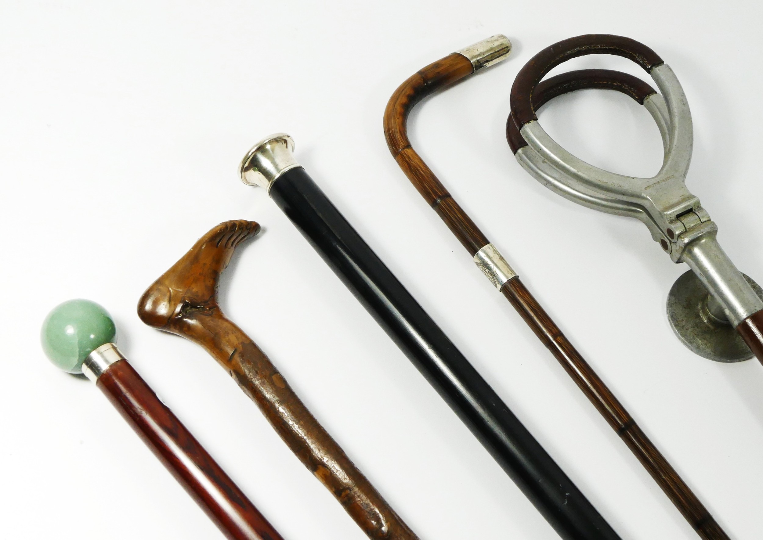 A collection of walking sticks and canes, to include a silver sleeved cane with green agate