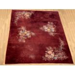 A wool carpet, with burgundy field and floral decoration, 265 x 365cm.