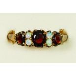 An Edwardian three stone garnet ring with opal points between, V, 3.4gm.