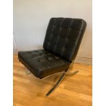 A contemporary Barcelona style chair, upholstered in black button back leather, raised on a polished