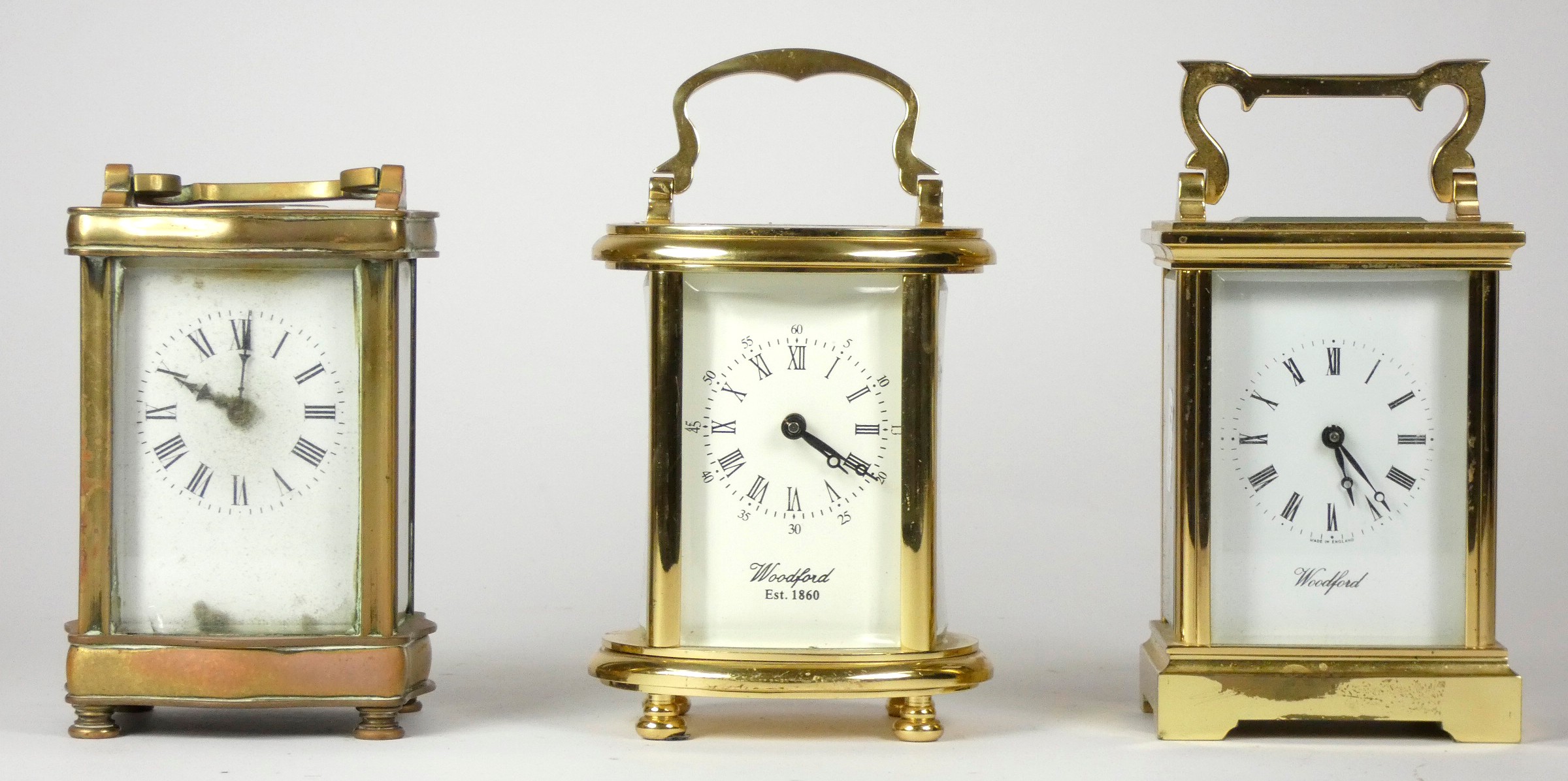 Three mid 20th Century brass carriage clocks, white enameled dials with Roman numerals, beveled edge