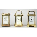 Three mid 20th Century brass carriage clocks, white enameled dials with Roman numerals, beveled edge