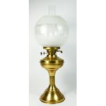 A brass column oil lamp, with frosted etched glass shade with chimney, raised on a circular