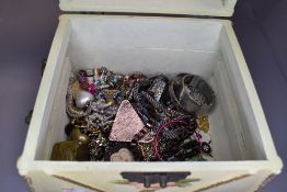 A painted treen jewellery casket containing a selection of metal jewellery including chains, bangles
