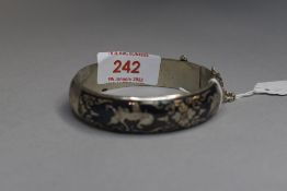 A white metal hinged bangle stamped Thailand/ Siamese having Niello enamelled Oriental decoration,