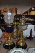 Two brass based oil lamps one with blue glass well complete with shade and chimney the other clear