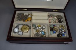 A wood effect jewellery case containing a selection of costume jewellery including clip earrings,