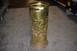 A brass pressed stick or umbrella stand with pressed crest motif