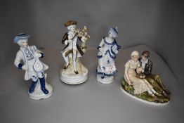 Four ceramic figurines including musicians and couple seated on grass.