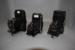 Three folding pocket cameras. An Ibsor, a Triumph and a Voigtlander