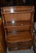 An Ercol mid elm tiered bookshelf with cupboard base