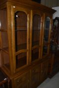 A modern stained frame full height display cabinet/bookcase, having glass top and cupboards under, w