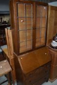 A 1950's oak bureau bookcase having leaded glass top with fall front and drawers, w 66cm
